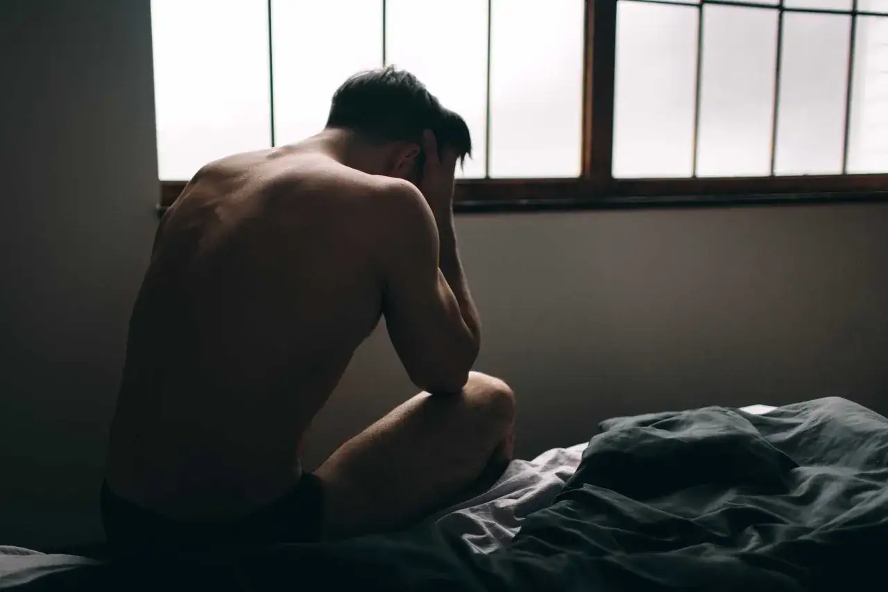 Man sitter p&aring; s&auml;ngkanten med h&auml;nderna &ouml;ver ansiktet, m&ouml;rkt rum med f&ouml;nster i bakgrunden. En k&auml;nsla av oro, men det finns hopp om att s&aring; f&aring;r du tillbaka potensen.