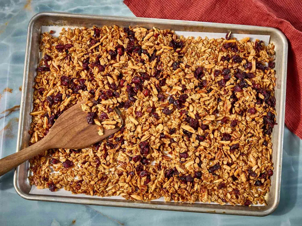 En pl&aring;t med hemmagjord crunchy granola med torkade tranb&auml;r och mandel. En tr&auml;sked ligger i granolan.