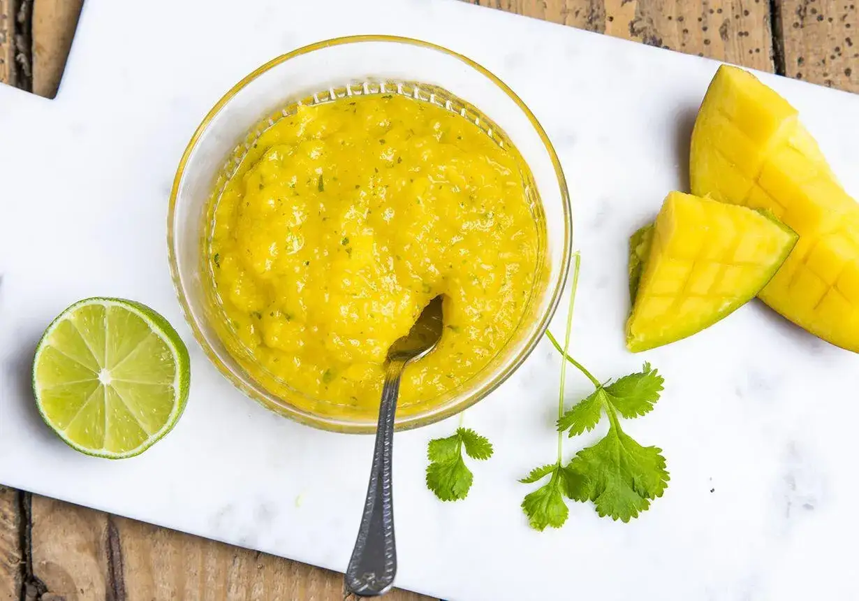 En sk&aring;l med gul mango dressing, limeklyfta, mangobitar och koriander. Perfekt f&ouml;r en somrig sallad.