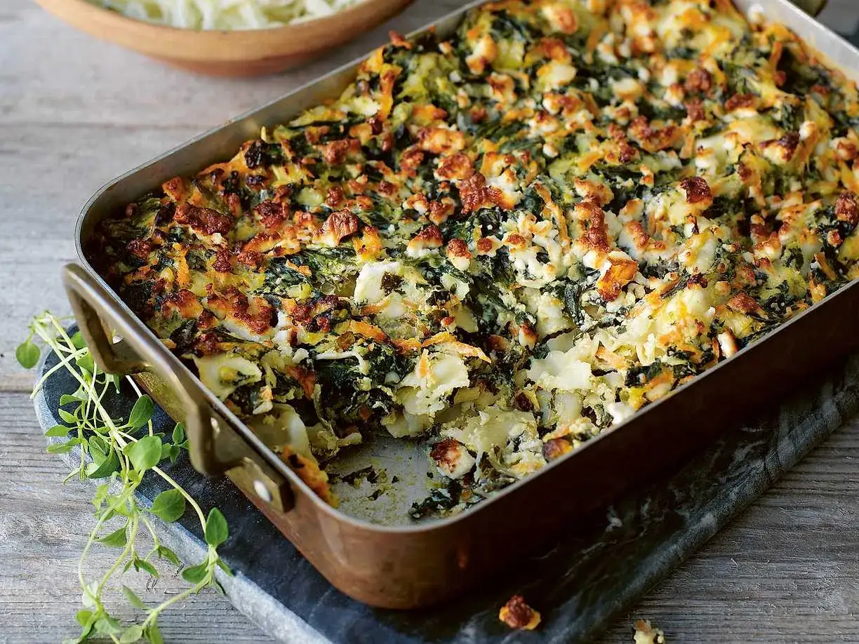 En gyllene, nyttig lasagne med spenat och ost i en kopparform. Serveras med f&auml;rska &ouml;rter.