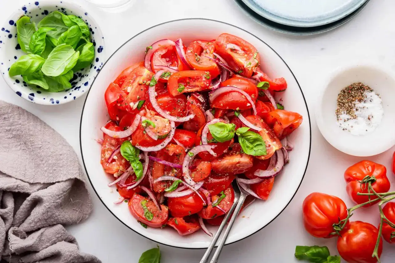 En fräsch tomatsallad med rödlök och basilika. Perfekt som tillbehör, med lågt tomat kcal-innehåll.
