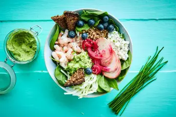 En skål med räkor, grönsaker, bär och krispigt bröd. En härlig representation av nordisk kost, full av färska smaker och nyttigheter.